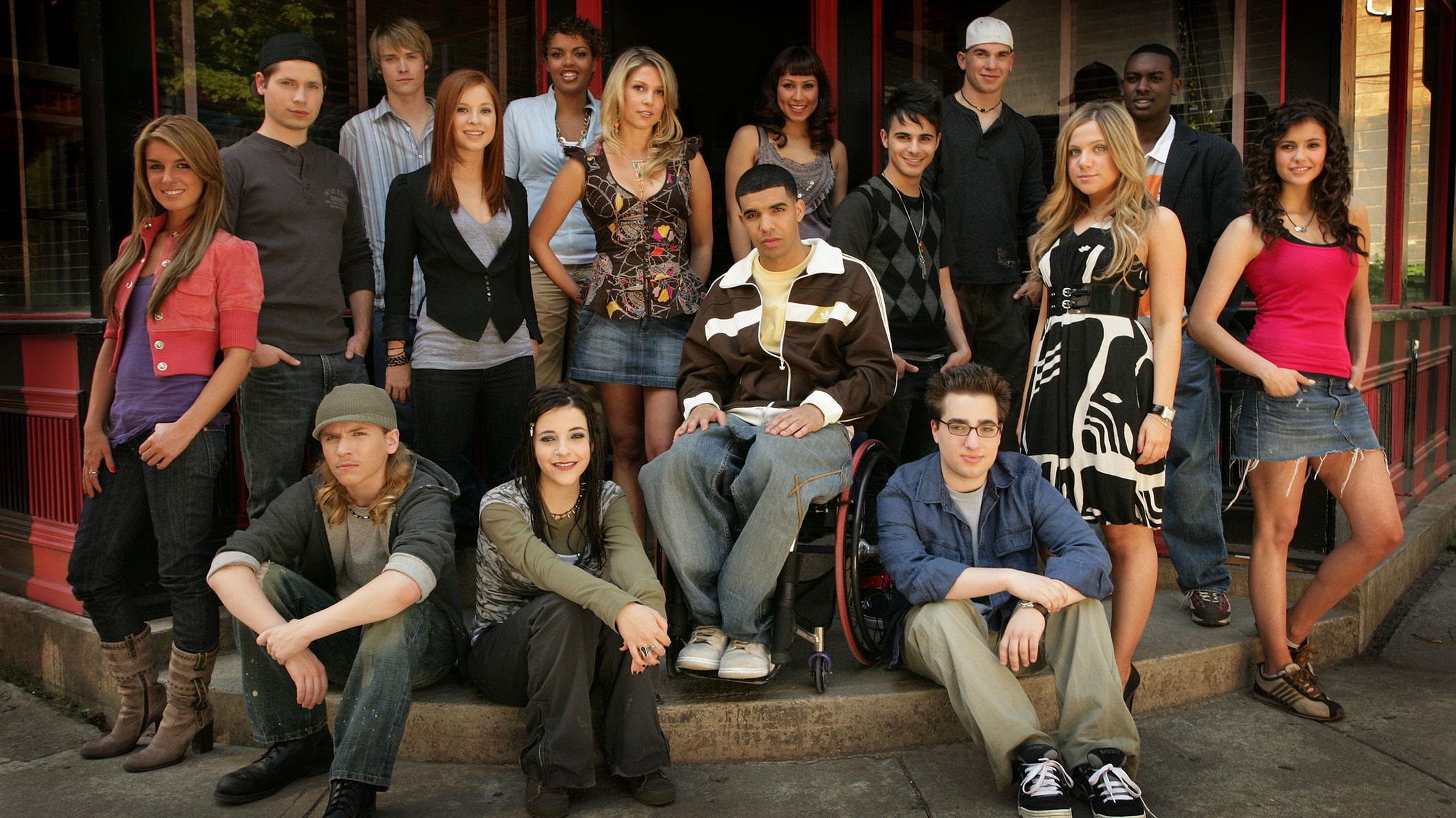 A group of teenagers posing for a picture outside.