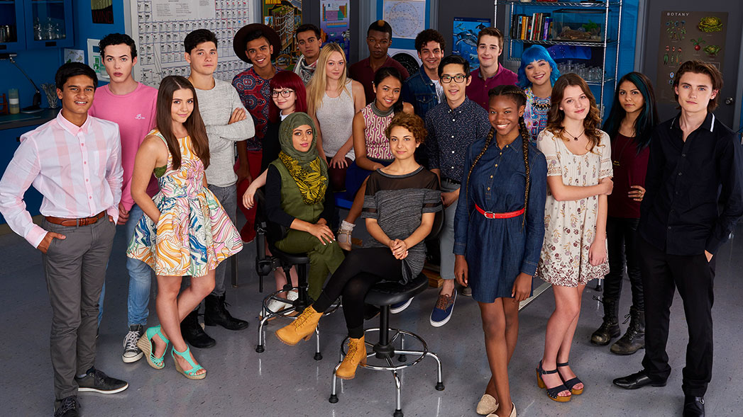 A multicultural group of teenagers posing for a picture inside a classroom.